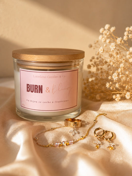 Translation missing: fr.Bougie Burn &amp; Bling de Loredana Candles &amp; Co, pot en verre et couvercle en bambou, étiquette rose, posée près de fleurs séchées